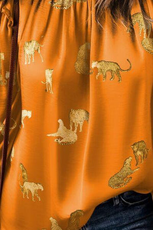 a close up of a person wearing an orange shirt with animals on it