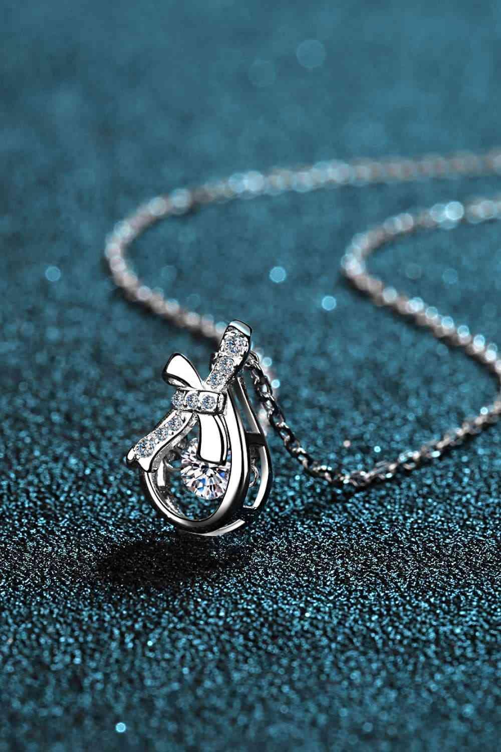 a diamond pendant on a chain on a blue surface