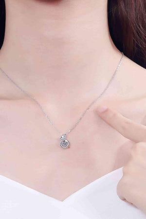 a woman wearing a necklace with a diamond on it