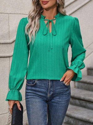 a woman wearing a green blouse and jeans