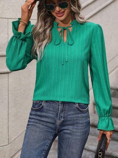 a woman wearing a green blouse and jeans