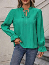 a woman wearing a green blouse and jeans