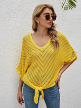 a woman wearing a yellow sweater and sunglasses