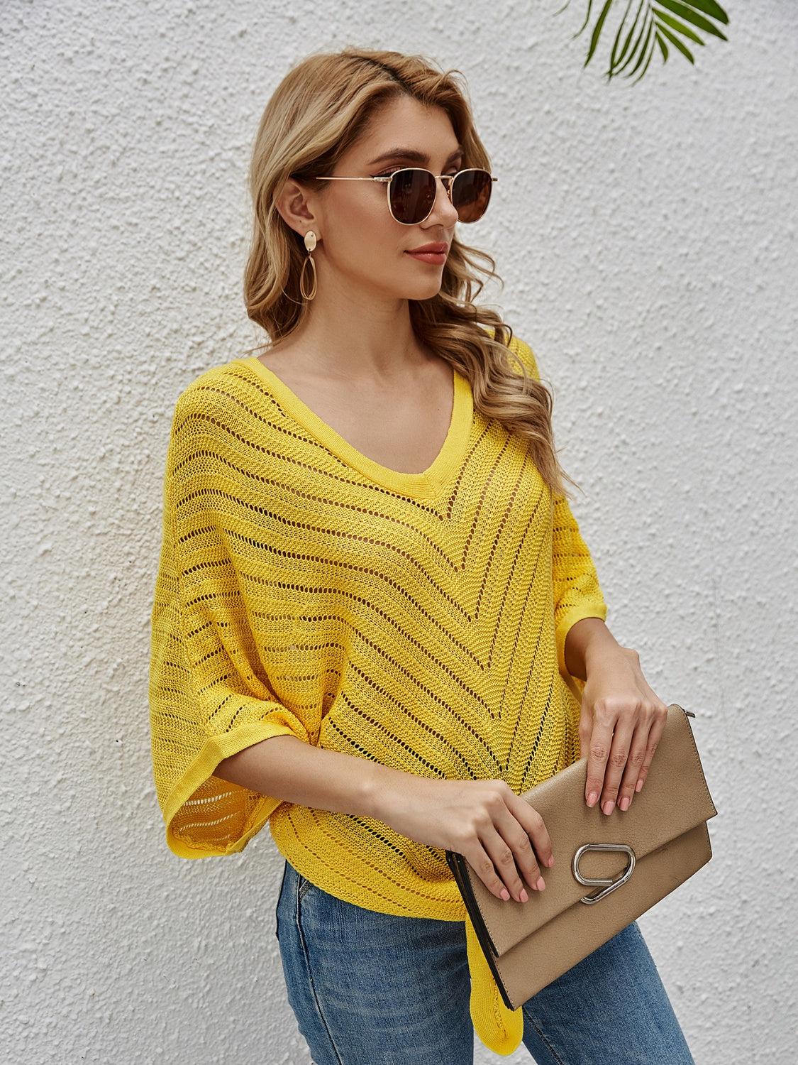 a woman in a yellow sweater holding a tan purse