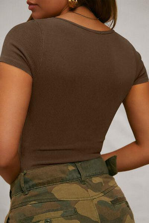 a woman wearing a brown shirt and camo shorts