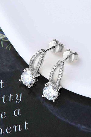 a pair of white diamond earrings sitting on top of a table