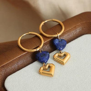 a pair of heart shaped earrings sitting on top of a table