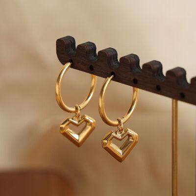 a pair of gold earrings hanging from a hook