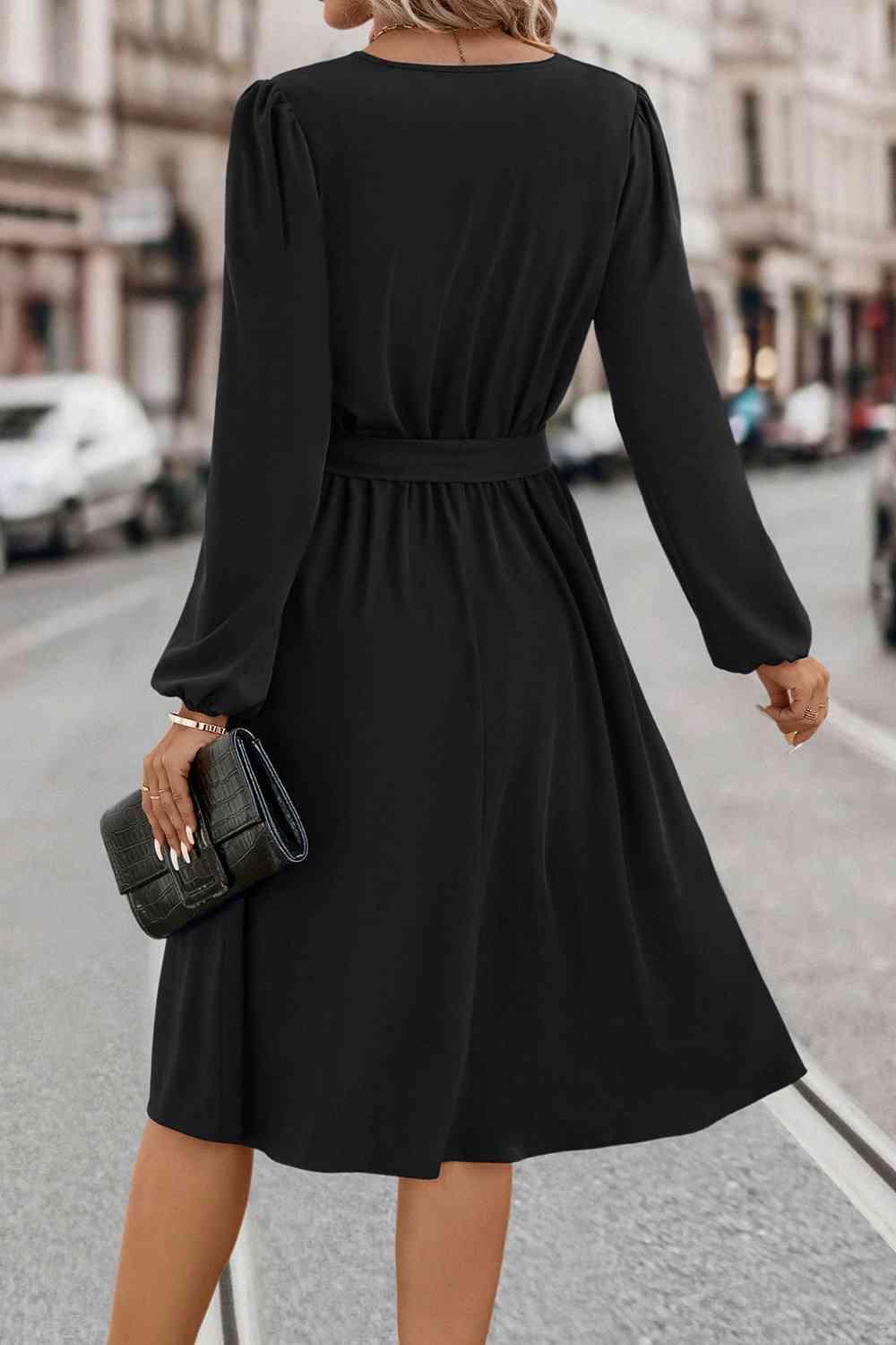 a woman in a black dress is walking down the street