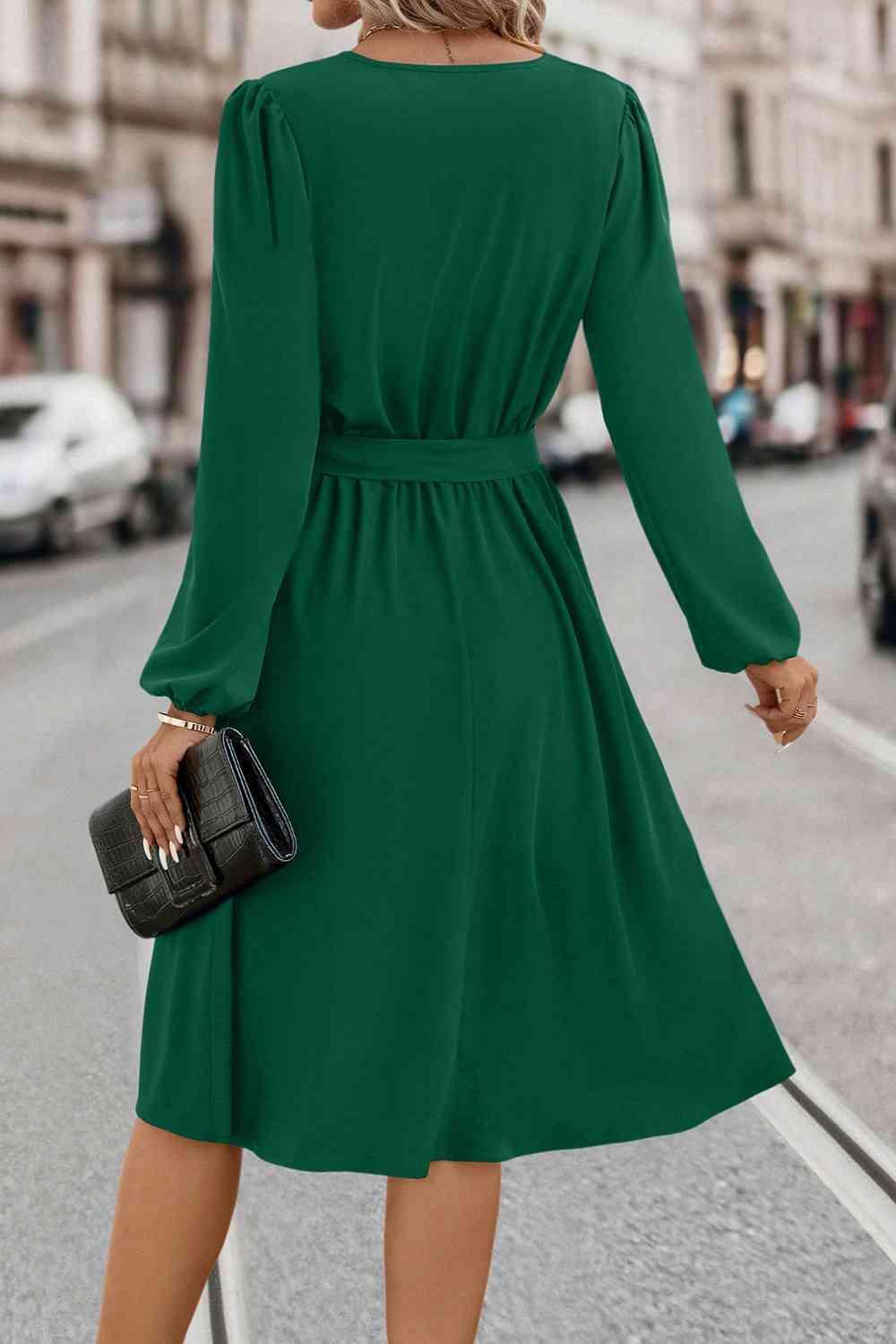 a woman in a green dress is walking down the street