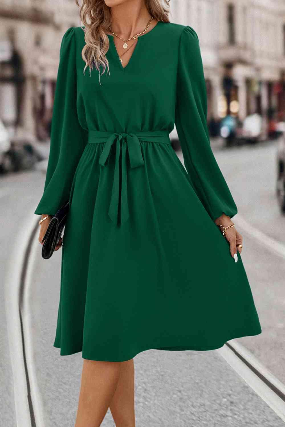 a woman in a green dress is walking down the street