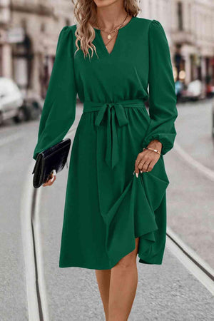 a woman in a green dress is walking down the street