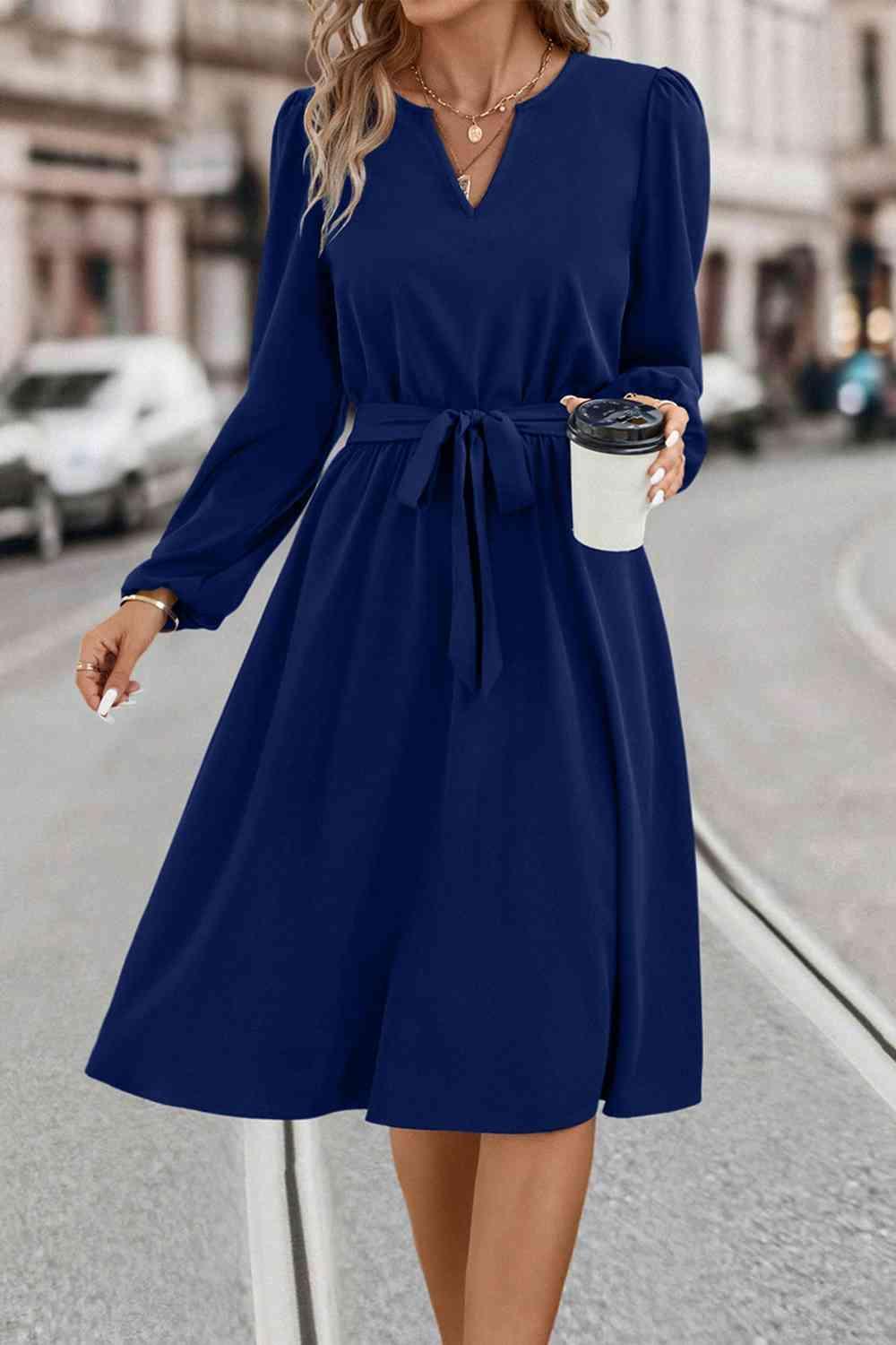 a woman in a blue dress holding a cup of coffee