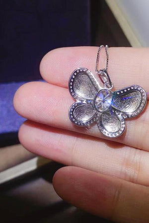 a person is holding a silver necklace with a flower on it