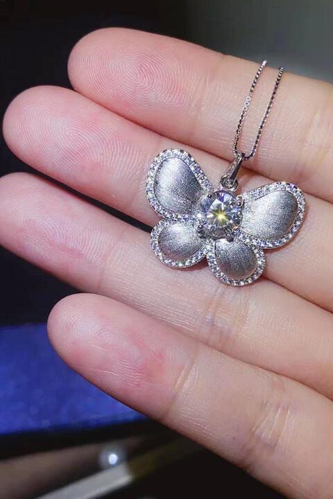 a person is holding a silver flower necklace