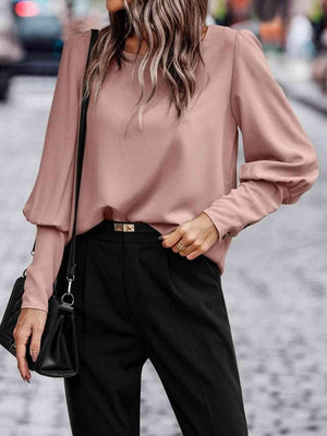 a woman wearing a pink blouse and black pants