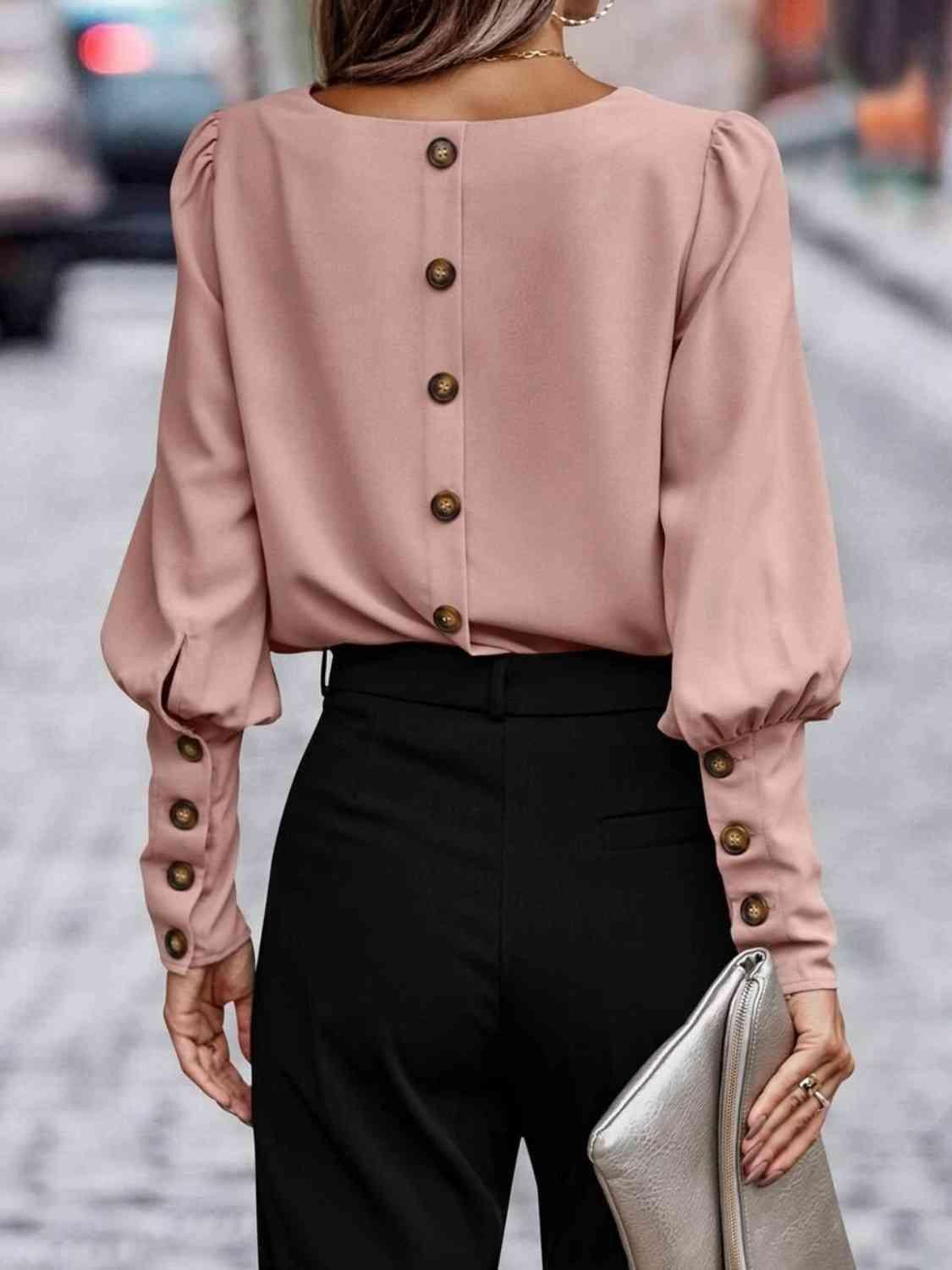 a woman wearing a pink blouse and black pants