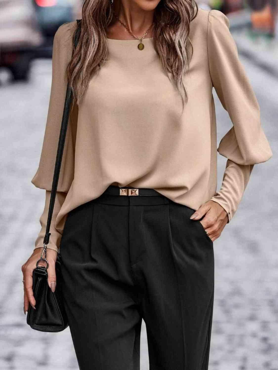 a woman wearing a tan top and black pants