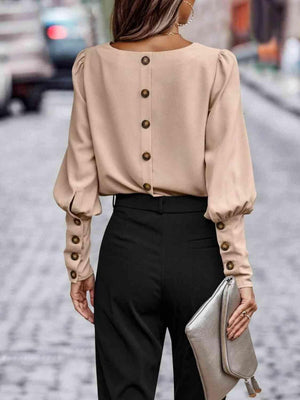 a woman wearing a beige blouse and black pants