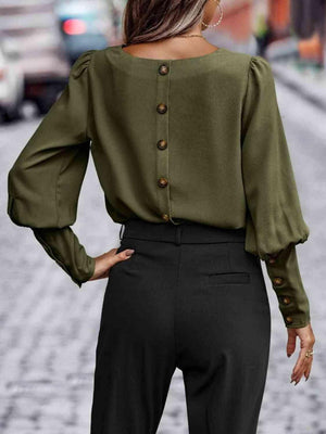 a woman wearing a green blouse and black pants