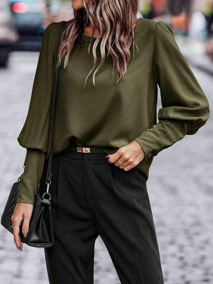 a woman wearing a green blouse and black pants