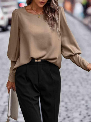 a woman wearing a tan top and black pants