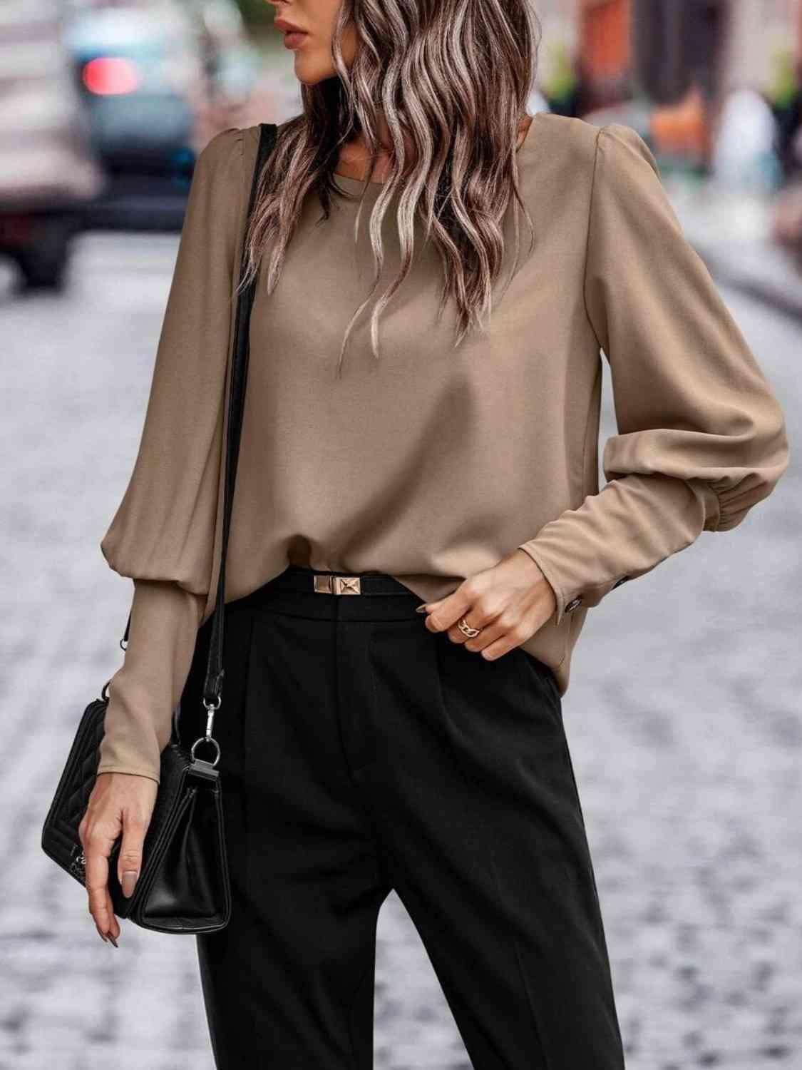 a woman wearing a tan top and black pants