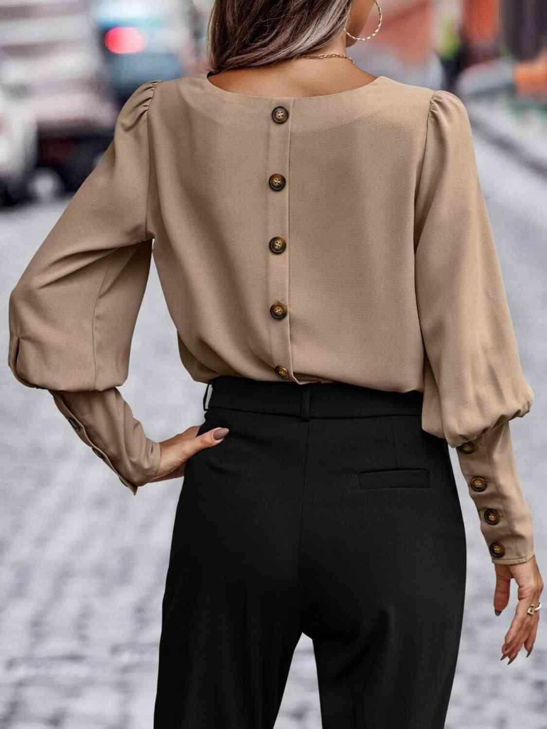 a woman wearing a tan blouse and black pants