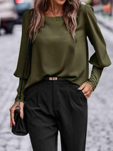 a woman wearing a green blouse and black pants