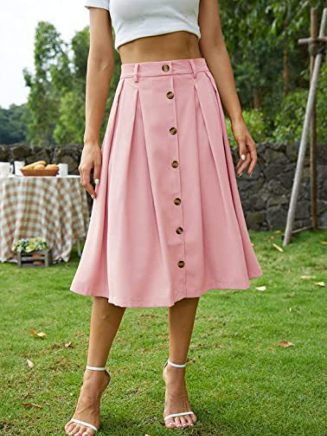 a woman standing in a field wearing a pink skirt