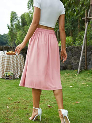 a woman in a pink skirt standing in the grass