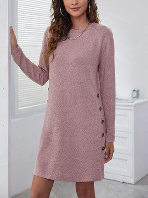 a woman standing in a room wearing a pink sweater dress