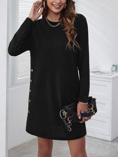 a woman wearing a black sweater dress with gold buttons