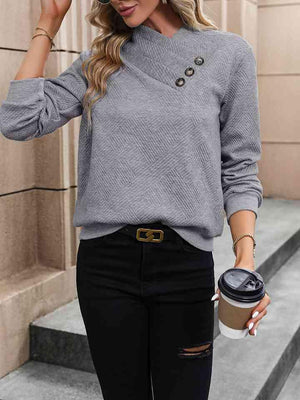 a woman wearing a grey sweater and black ripped jeans