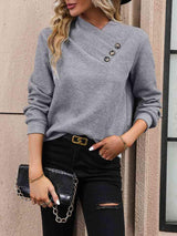 a woman wearing a grey sweater and black ripped jeans