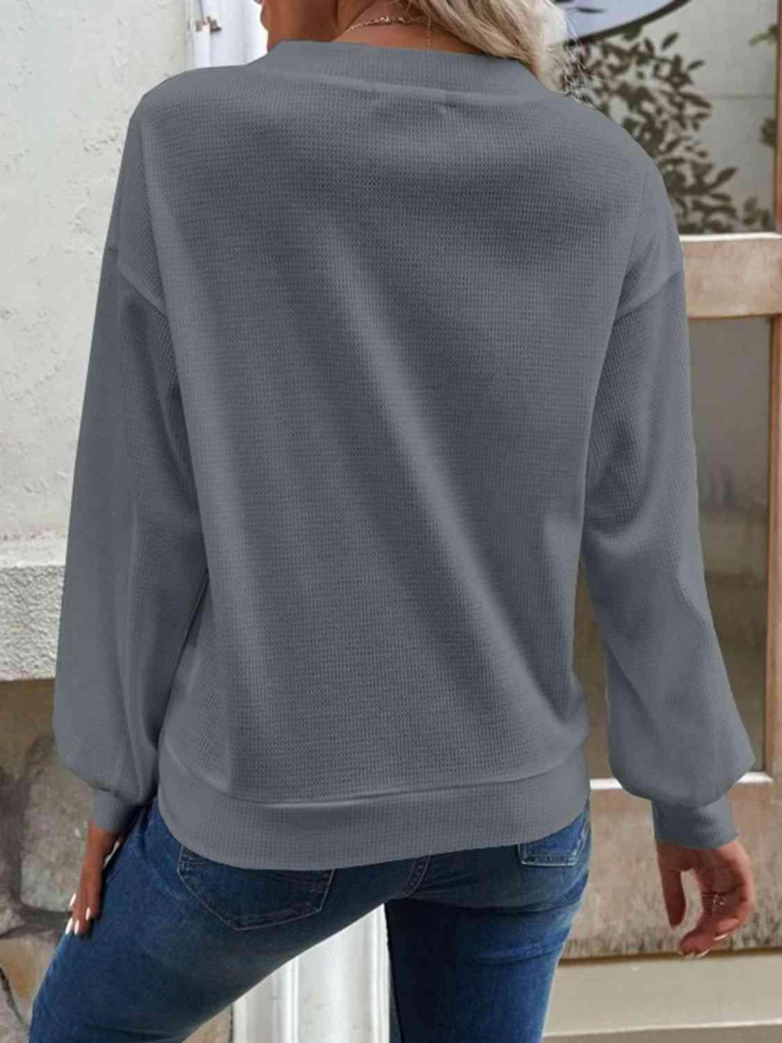 a woman wearing a grey sweater and jeans