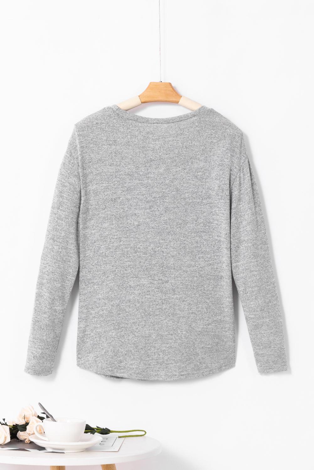 a gray sweater hanging on a white wall