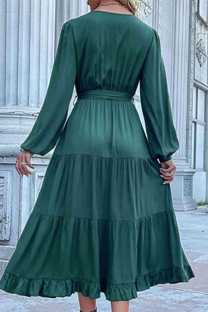 a woman in a green dress standing on a sidewalk