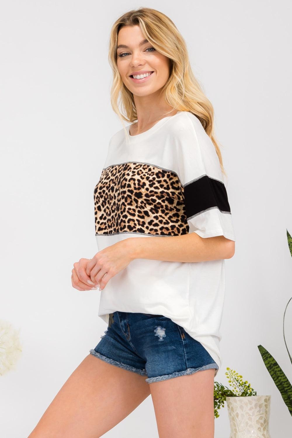 a woman wearing a white top with a leopard print on it