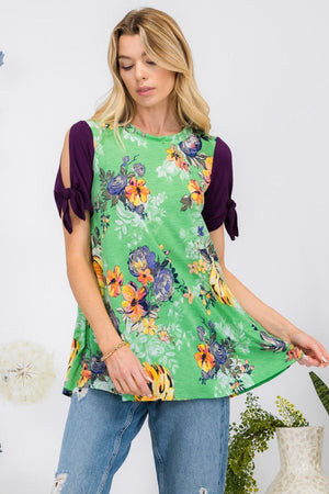 a woman wearing a green floral top with purple sleeves