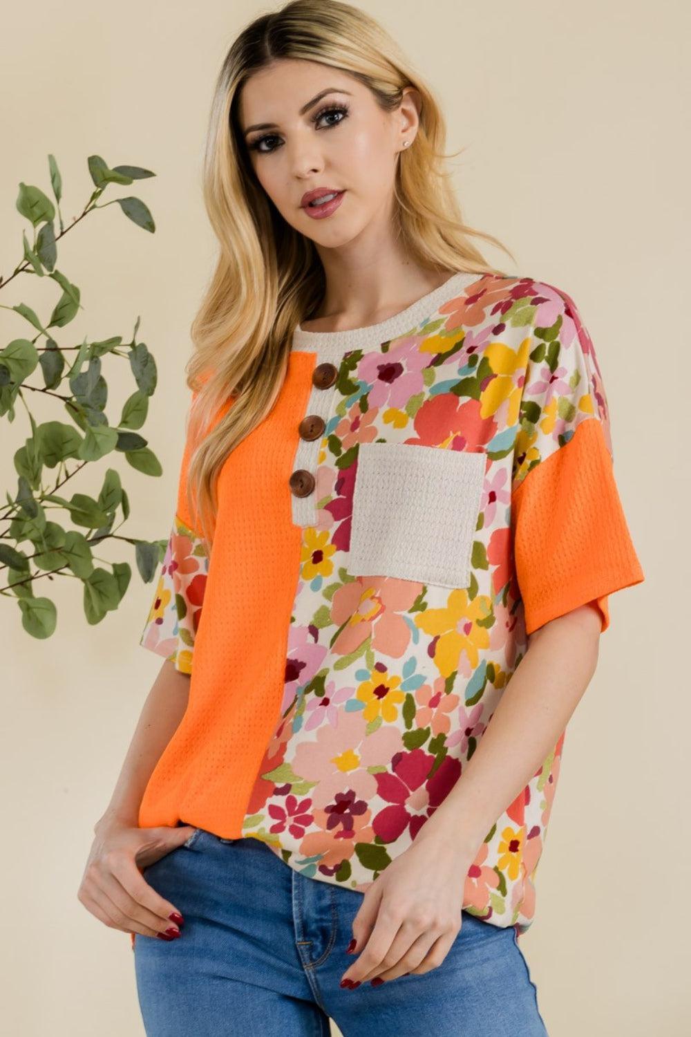 a woman wearing a floral top with an orange cardigan