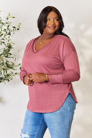 a woman standing next to a plant wearing a pink shirt