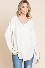 a woman wearing a white sweater and ripped jeans