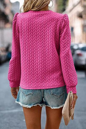 a woman wearing a pink sweater and denim shorts