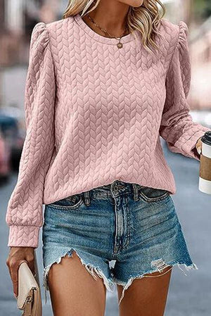 a woman wearing a pink sweater and denim shorts