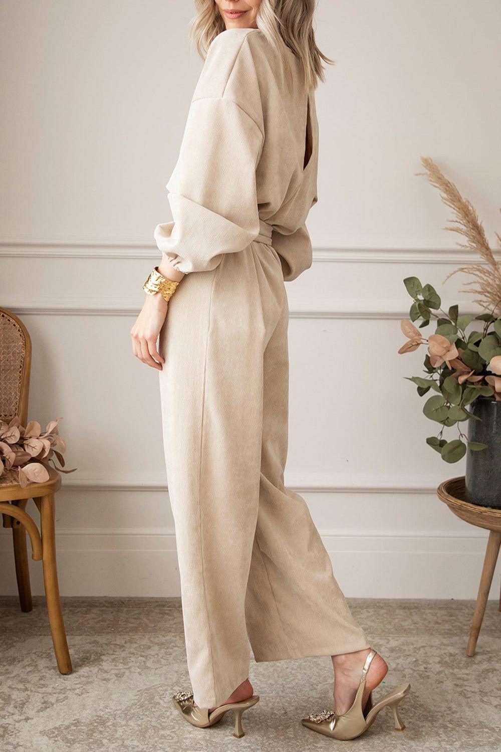 a woman standing in a room wearing a beige jumpsuit