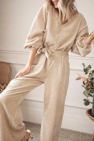 a woman in a beige jumpsuit posing for a picture