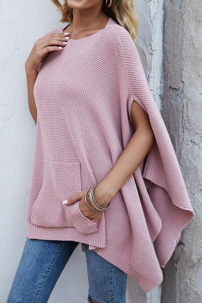 a woman in a pink sweater leaning against a wall