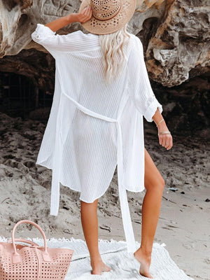 a woman in a white dress and hat on the beach