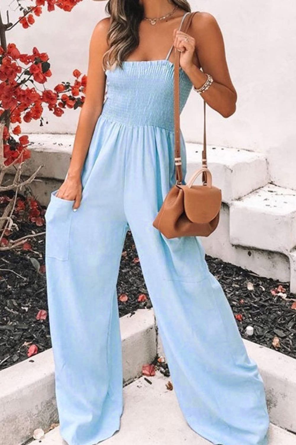 a woman in a blue jumpsuit holding a purse